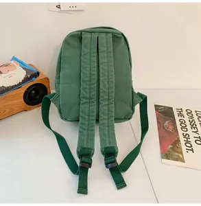 Vista trasera de mochila de lona verde con correas anchas ajustables y diseño retro