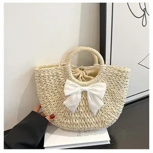 Détail d'un sac demi-lune en paille beige avec grand nœud en soie et doublure à cordon