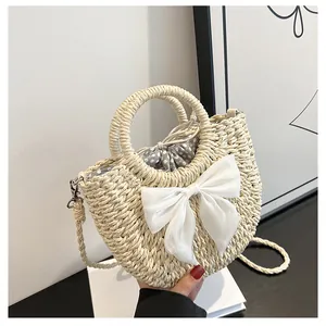 Détail du sac en paille tissé main avec grand nœud en satin blanc et doublure à pois