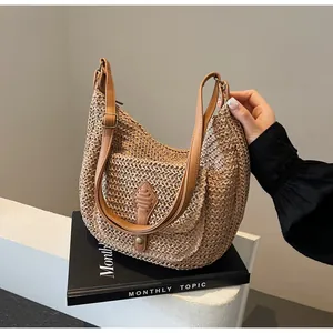 Detail of woven straw saddle bag with brown leather strap and front pocket detail