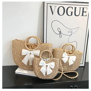 Ensemble de trois sacs en paille tressée avec des nœuds en soie blanche pour les vacances