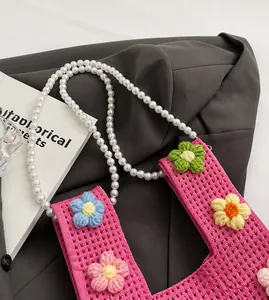 Détail du sac seau en tricot rose avec fleurs au crochet et bandoulière perles