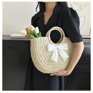 Vue détaillée d'un sac demi-lune en paille tressée avec un nœud en satin blanc et anses rondes