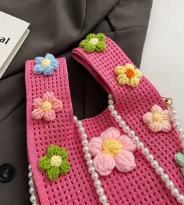 Détail du sac seau rose en tricot avec crochet floral et chaîne de perles élégante