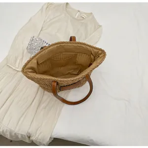 Détail du sac cabas en paille tissée avec anses en cuir marron et poche zippée interne
