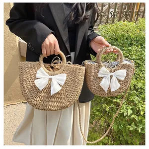 Détail de sacs en paille tressés avec des nœuds blancs et une doublure à cordon