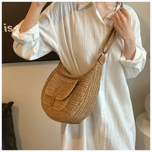 Close-up of woven straw texture and faux leather buckle on a beach hobo shoulder bag