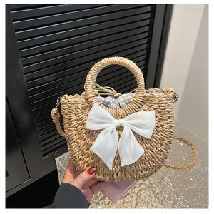 Détail d'un sac en paille avec un nœud en gaze blanche et une doublure à pois
