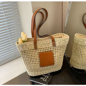 Détails d'un sac cabas en paille tressée avec poignées et empiècement en cuir marron