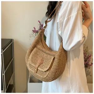 Detail of hand-woven straw shoulder bag featuring brown leather trim and toggle closure