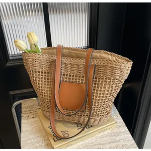 Détail d'un sac cabas en paille tressée avec bretelles en cuir et poche frontale