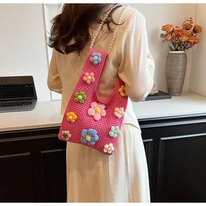 Detalle de bolso saco de punto rosa con flores en 3D y elegante correa de perlas blancas