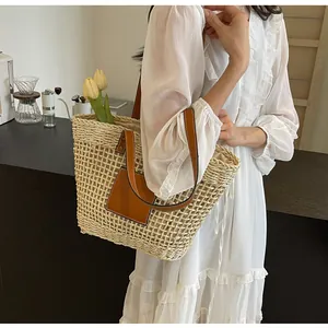 Gros plan sur un sac cabas en paille tissée main avec anses en cuir brun et fleurs