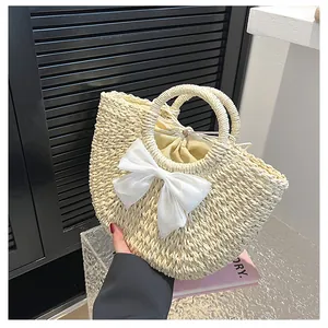 Détail de la texture d'un sac en paille demi-lune avec nœud en soie et cordon