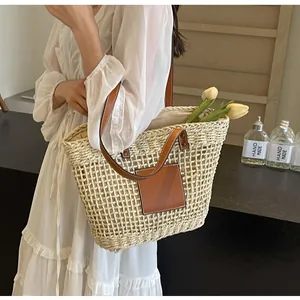 Détail d'un sac cabas en paille tissé à la main avec anses en cuir brun et doublure tissu