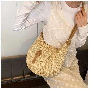 Detailed close-up of woven straw shoulder bag with brown leather strap and gold buckle