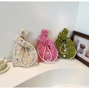 Drei gestrickte Handtaschen in Elfenbein, Rosa und Oliv mit Perlenketten auf einem Podest
