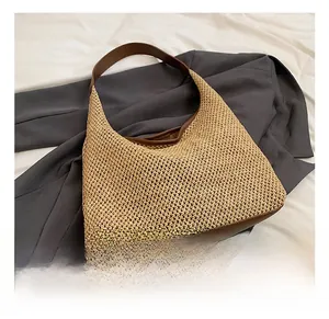 Dettaglio borsa a spalla in paglia intrecciata con finiture in pelle su blazer grigio