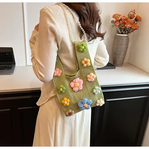Detalle de bolso saco de punto con cadena de perlas y flores 3D de colores vivos