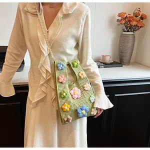 Detalle del bolso de punto verde con flores de ganchillo 3D y cadena de perlas