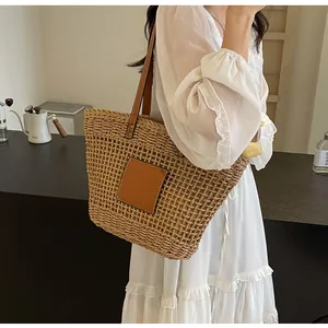 Détail du sac cabas en paille tressée avec empiècement en cuir marron et bandoulière