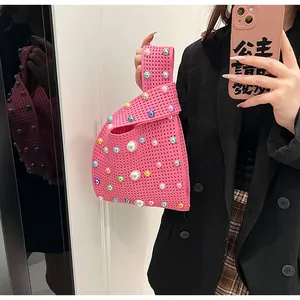 Detail der gehäkelten Knotentasche in Rosa mit bunten Perlen über einem schwarzen Blazer