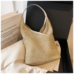 Dettaglio della trama a maglia vuota tessuta a mano su una borsa hobo in paglia beige