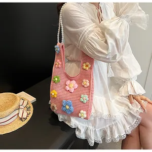 Detalle de bolso saco de ganchillo rosa con flores 3D y asa de cadena de perlas