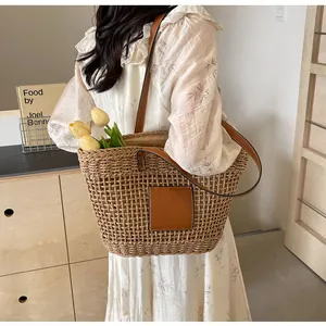 Détail du sac cabas en paille tissée avec empiècement en cuir marron pour les vacances d'été