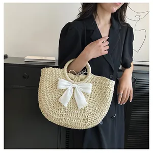 Vue détaillée du sac en paille demi-lune avec nœud en soie blanc et doublure à cordon