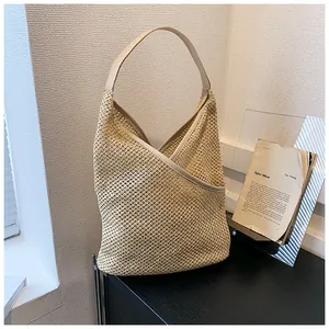 Dettaglio della trama beige intrecciata e bordo in pelle su una borsa hobo in paglia