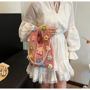Detalle del bolso tipo saco de ganchillo rosa con flores 3D y correa de perlas