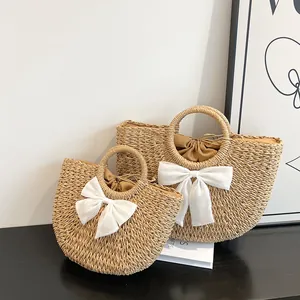 Détail de sacs en paille de deux tailles avec nœuds blancs et doublure à cordon