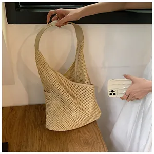 Dettaglio della borsa hobo in paglia intrecciata con trama a rete e tracolla larga