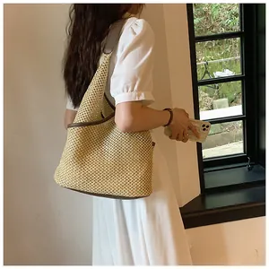 Dettaglio della borsa tote in paglia intrecciata con finiture in pelle marrone e spazio