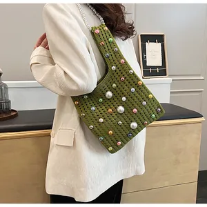 Detail der grünen Stricktasche mit bunten Perlen und großem weißen Perlenriemen