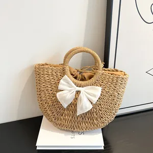 Détail du sac en paille tressée avec nœud en mousseline blanche et doublure à cordon