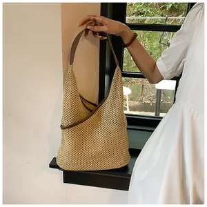 Dettaglio della borsa tote in paglia intrecciata a mano con manici in pelle marrone