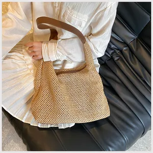 Dettaglio della borsa a spalla in paglia intrecciata con tracolla in pelle marrone