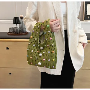 Detail der handgewebten grünen Strickhandtasche mit bunten Perlen und weißer Perlenkette