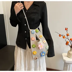 Detalle de bolso tipo cubo de ganchillo con flores 3D y correa de hombro de perlas