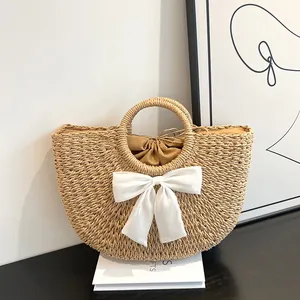 Vue détaillée du sac en paille demi-lune avec nœud blanc et doublure intérieure