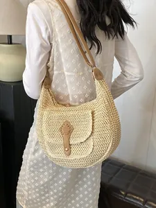 Large beige woven straw hobo bag with brown leather strap and front pocket detail