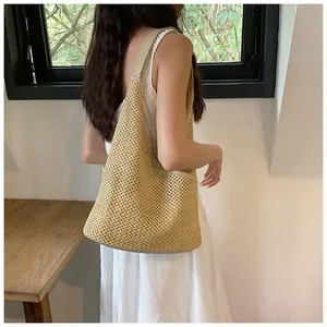 Dettaglio della borsa tote in paglia beige con trama naturale e tracolla a spalla