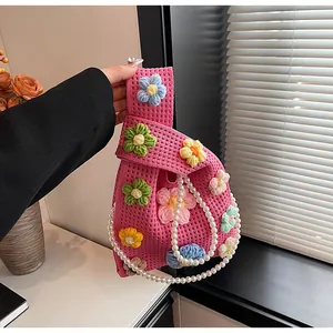 Detalle del bolso de punto rosa con flores de ganchillo 3D y cadena de perlas blanca