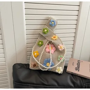 Detalle de bolso cubo de ganchillo hecho a mano con flores 3D y correa de perlas