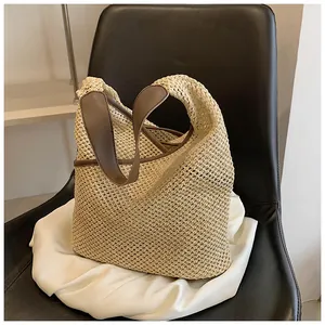 Dettaglio della borsa tote in paglia beige con manici in ecopelle marrone su raso