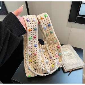 Detail der beigen Häkeltasche mit bunten Perlenakzenten und einer Perlenkette als Riemen