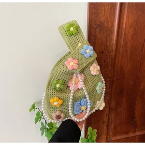 Detalle del bolso tipo cubo de ganchillo verde con flores 3D y elegante asa de perlas