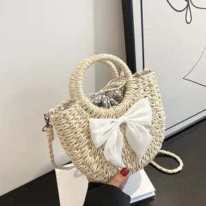 Détail du sac demi-lune en paille avec nœud en satin blanc et doublure à pois pratique